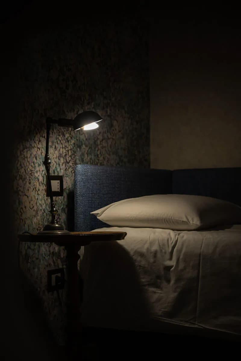 Softly lit bedroom at night with a bedside lamp by an empty bed